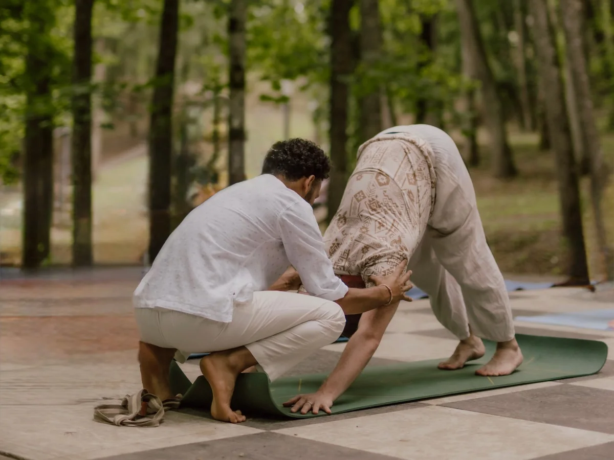 Naveen adjusting a student in downward dog